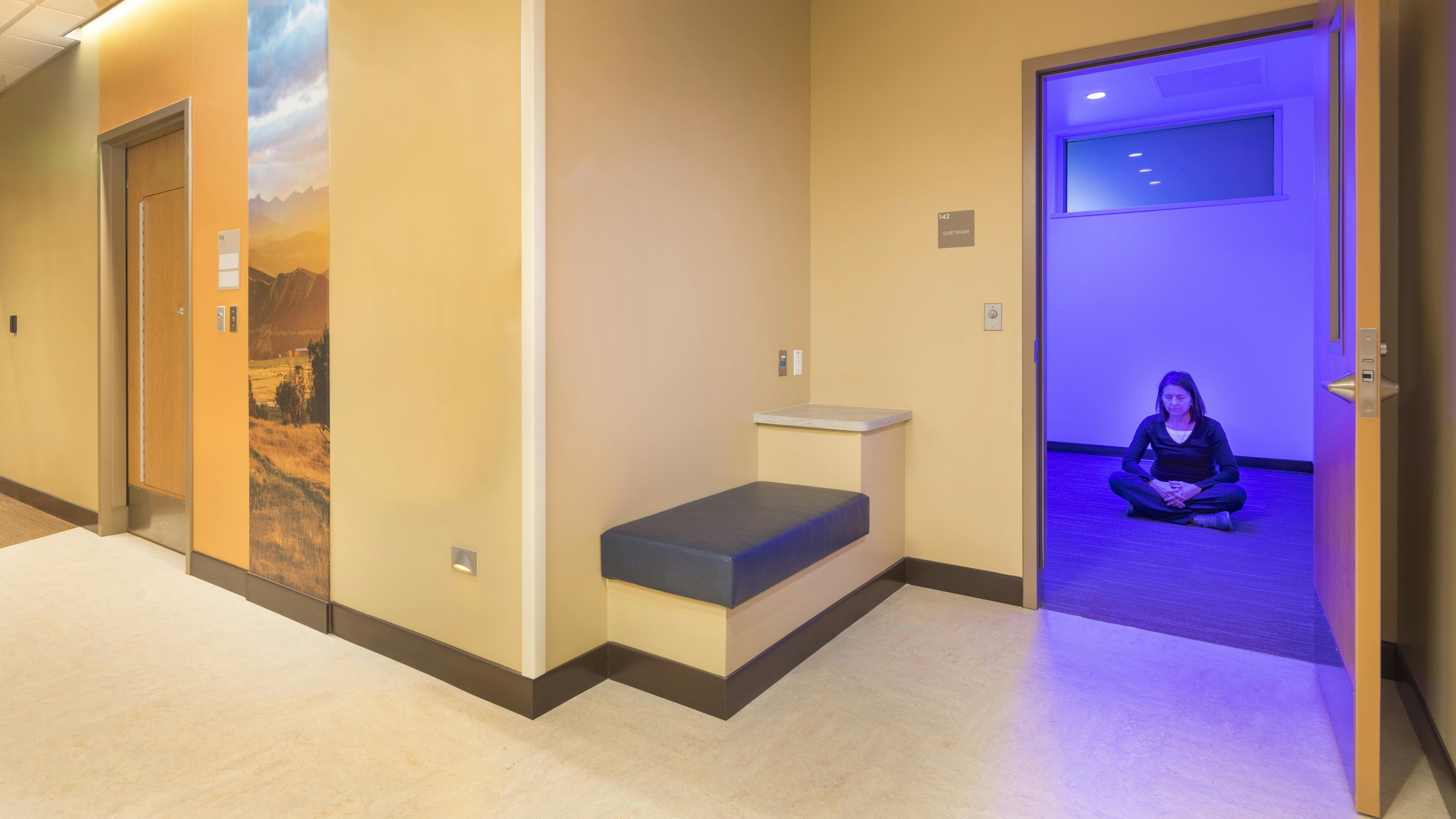 Quiet room in healthcare facility with woman seated in a meditation pose on the floor