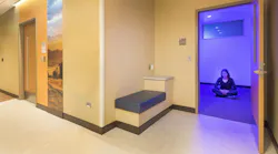 Quiet room in healthcare facility with woman seated in a meditation pose on the floor Quiet room in healthcare facility with woman seated in a meditation pose on the floor