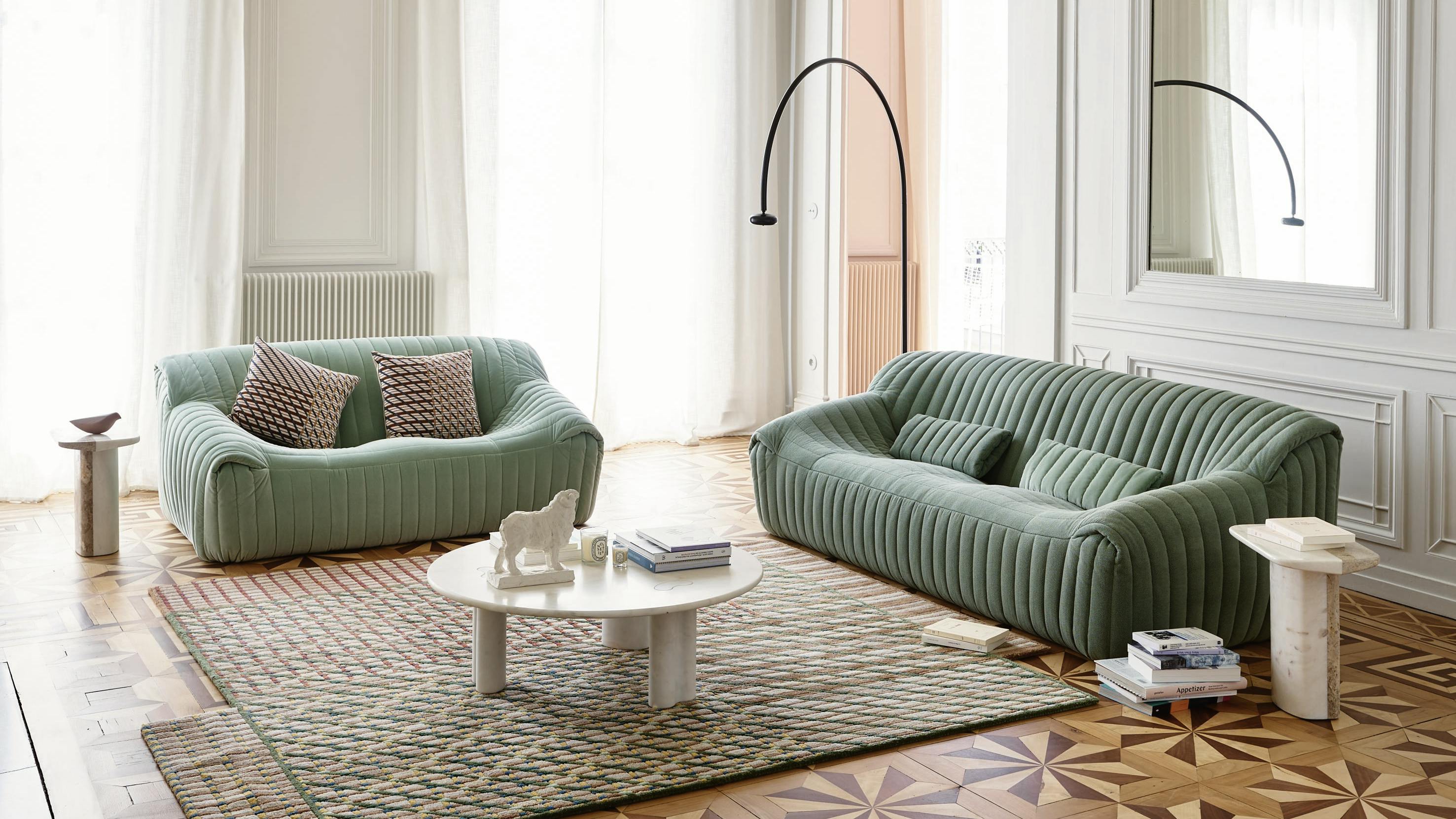 Sandra, designed by Annie Hi&eacute;ronimus for Ligne Roset, reintroduces an iconic, all-foam sofa. Two sofa are positioned in a living room and surrounded by side tables.