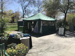 Stone-paved botanical garden walkway leading to an open green tent. Stone-paved botanical garden walkway leading to an open green tent.