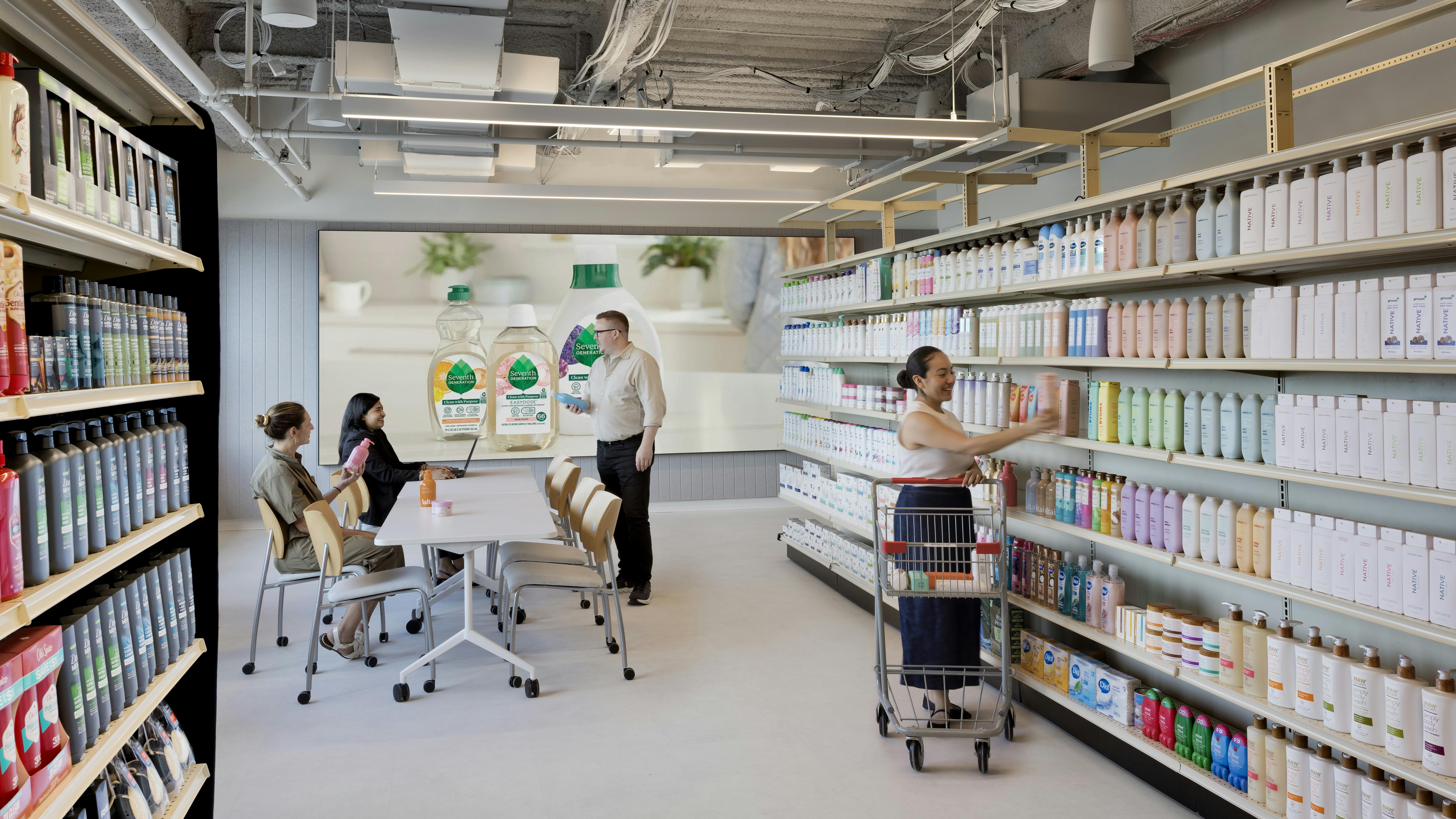 Unilever retail lab features personal care and beauty products on shelves, with focus-group consumers engaging with product and Unilever staff.
