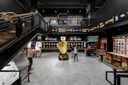 Central view of Rawling Experience Center shows baseball gloves and other memorabilia displayed along walls, an LED ribbon display between floors, and the staircase and balcony to second floor spaces. Central view of Rawling Experience Center shows baseball gloves and other memorabilia displayed along walls, an LED ribbon display between floors, and the staircase and balcony to second floor spaces.