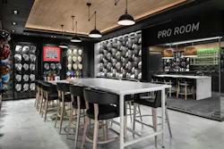 Suspended lighting illuminates a consultation area for custom glove designs, designed in black, white, gray, and neutral wood tones. Suspended lighting illuminates a consultation area for custom glove designs, designed in black, white, gray, and neutral wood tones.