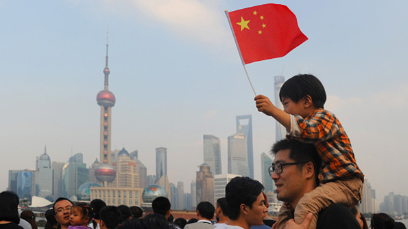 A Chinese boy waves a national flag from atop his fathers shoulders