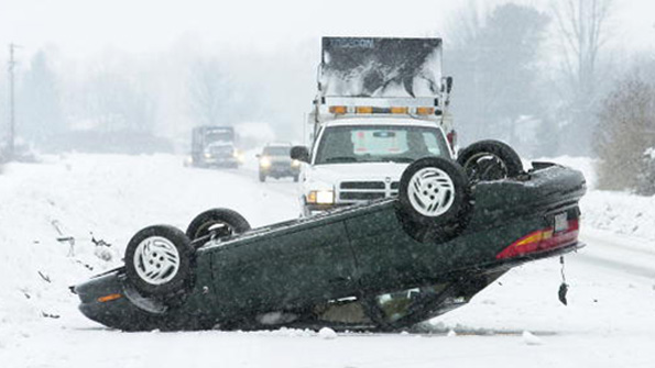 A flipped sedan blocks traffic in the snow