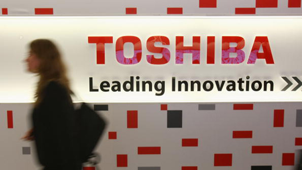 A woman walks pasts a Toshiba sign at a German tech fair