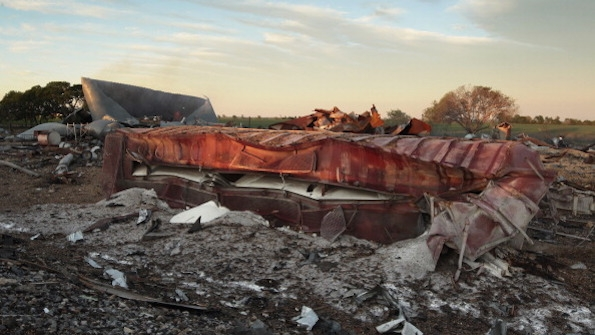A railroad boxcar filled with ammonium nitrate lay on its side near to the remains of the fertilizer plant that exploded in 2013