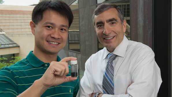 Rice University graduate student ChihChau Hwang left and Professor James Tour show a vial of material that that they say has the ability to capture carbon from gas flowing out of a well and hold it until it can be put back underground or otherwise used Credit Jeff FitlowRice University