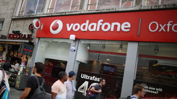 London shoppers walk past an Oxford Street Vodafone store