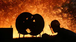 A Chinese steelworker labors in front of a blast furnace A Chinese steelworker labors in front of a blast furnace