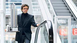 A man rides an escalator while carrying an architectural model A man rides an escalator while carrying an architectural model
