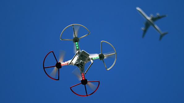 A recreational drone flies beneath a commercial airliner
