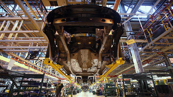 The underbelly of a car at an auto factory