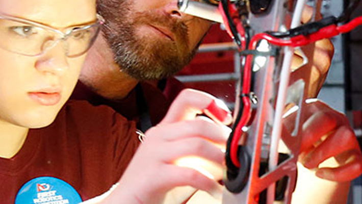 A high school student works on a robot as part of the FIRST Tech Challenge.