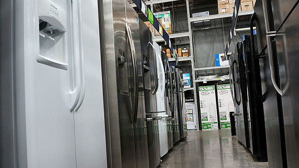 A row of refrigerators inside a big box store.