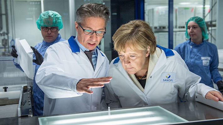 German chancellor Angela Merkel, right, visits a production facility for sterile glass vials at the Sanofi pharmaceuticals plants in Frankfurt.