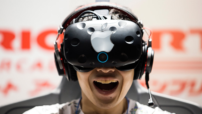 A man wears an HTC Vive with a superimposed Apple logo on it.