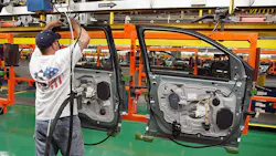A line worker handles a door at a Ford plant. A line worker handles a door at a Ford plant.