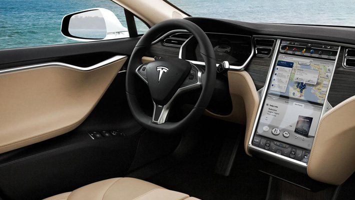 The steering wheel and dashboard user experience inside a Tesla Model S.