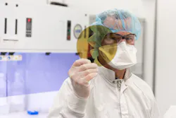 A scientist at SK Siltron CSS holds a silicon carbide wafer produced at the company's Michigan facility. A scientist at SK Siltron CSS holds a silicon carbide wafer produced at the company's Michigan facility.