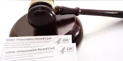 A gavel resting near CDC-issued COVID-19 vaccination record cards. A gavel resting near CDC-issued COVID-19 vaccination record cards.