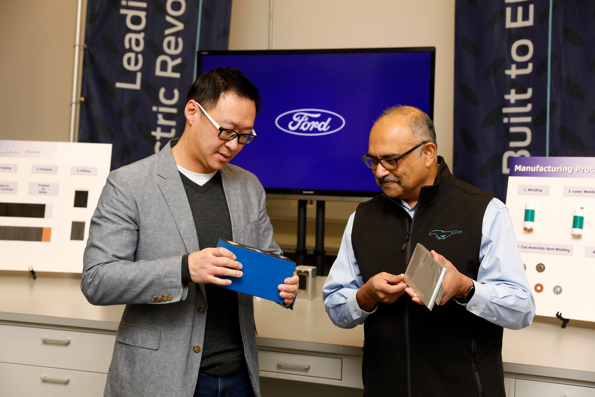 Charles Poon, Ford's director of Electrified Systems Engineering, holds a lithium iron phosphate (LFP) battery, while Anand Sankaran, director of Ford Ion Park holds a nickel cobalt manganese (NCM) battery. Ford currently uses NCM in its electric vehicles, and will add LFP to its lineup beginning later this year to help it produce more EVs and make them more accessible and affordable for customers.