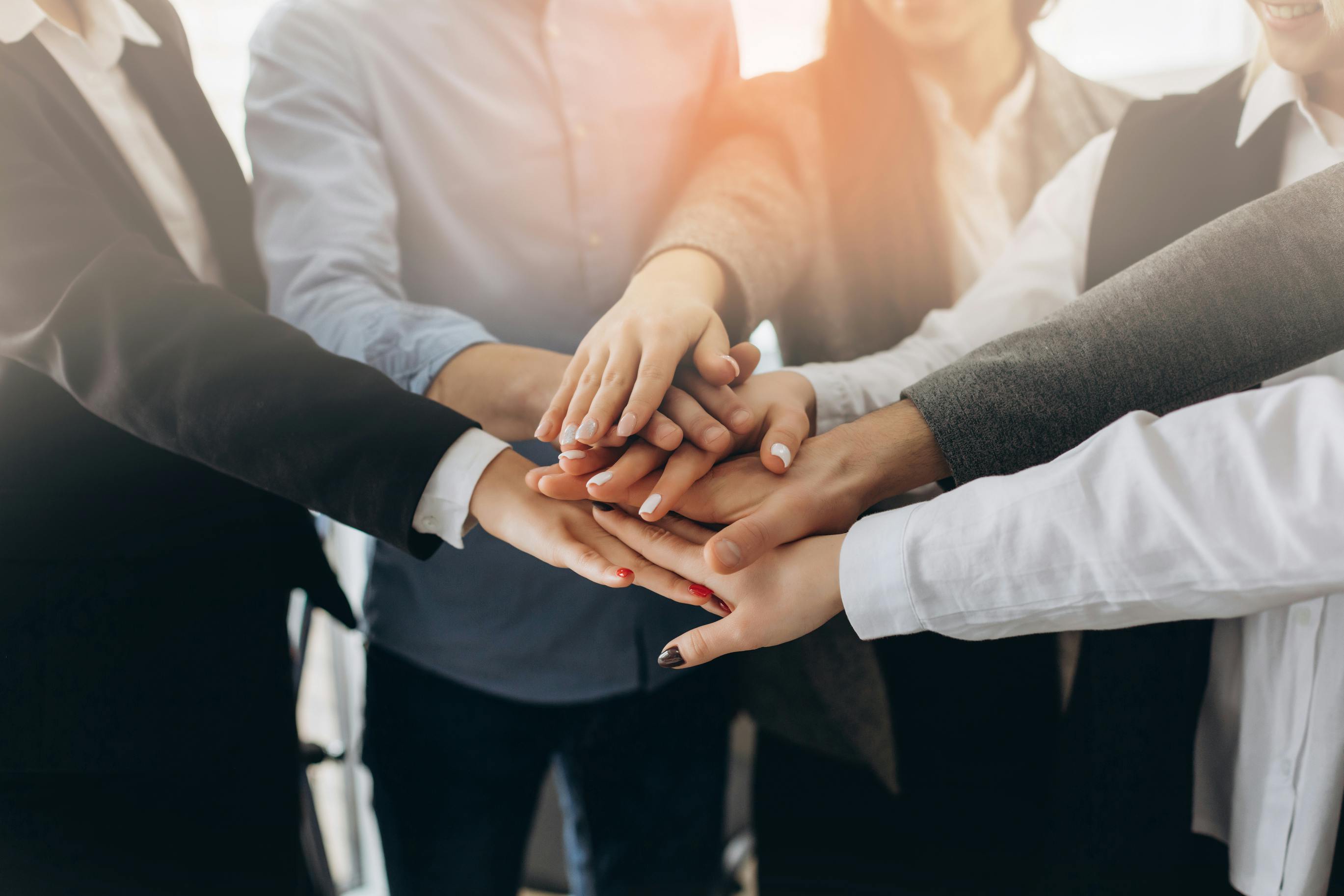 Close up top view of young business people putting their hands together.
