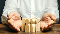 Businessperson holding wooden figurines. Businessperson holding wooden figurines.