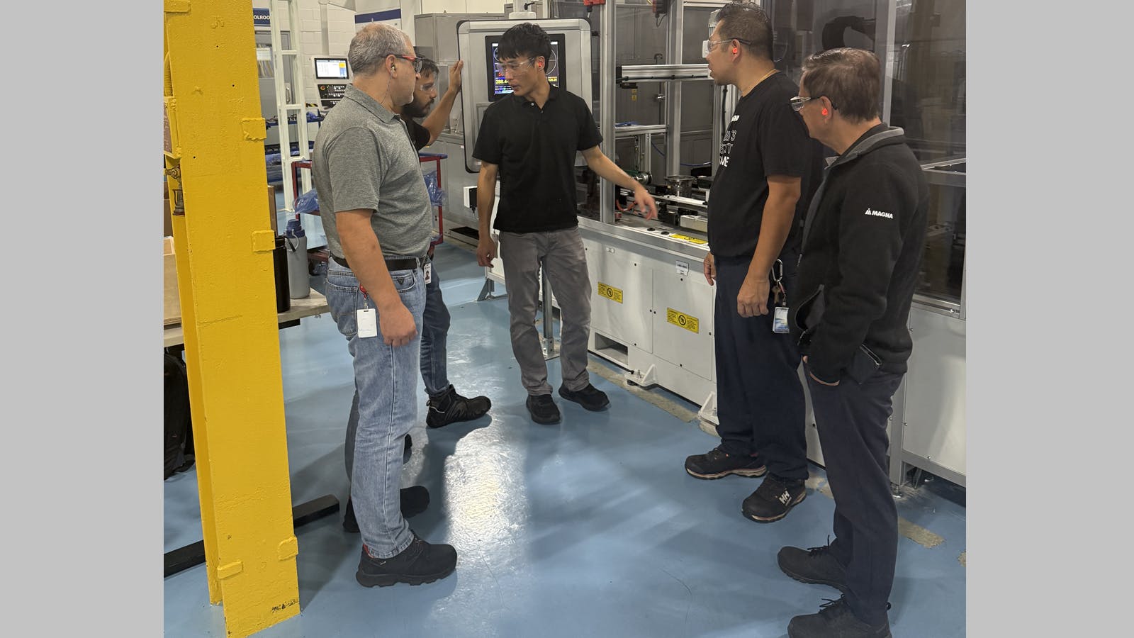 Pullmatic Mfg. Magna Powertrain team members on the Rivian line discuss progress on the project, including program manager Jacob Ham, center.