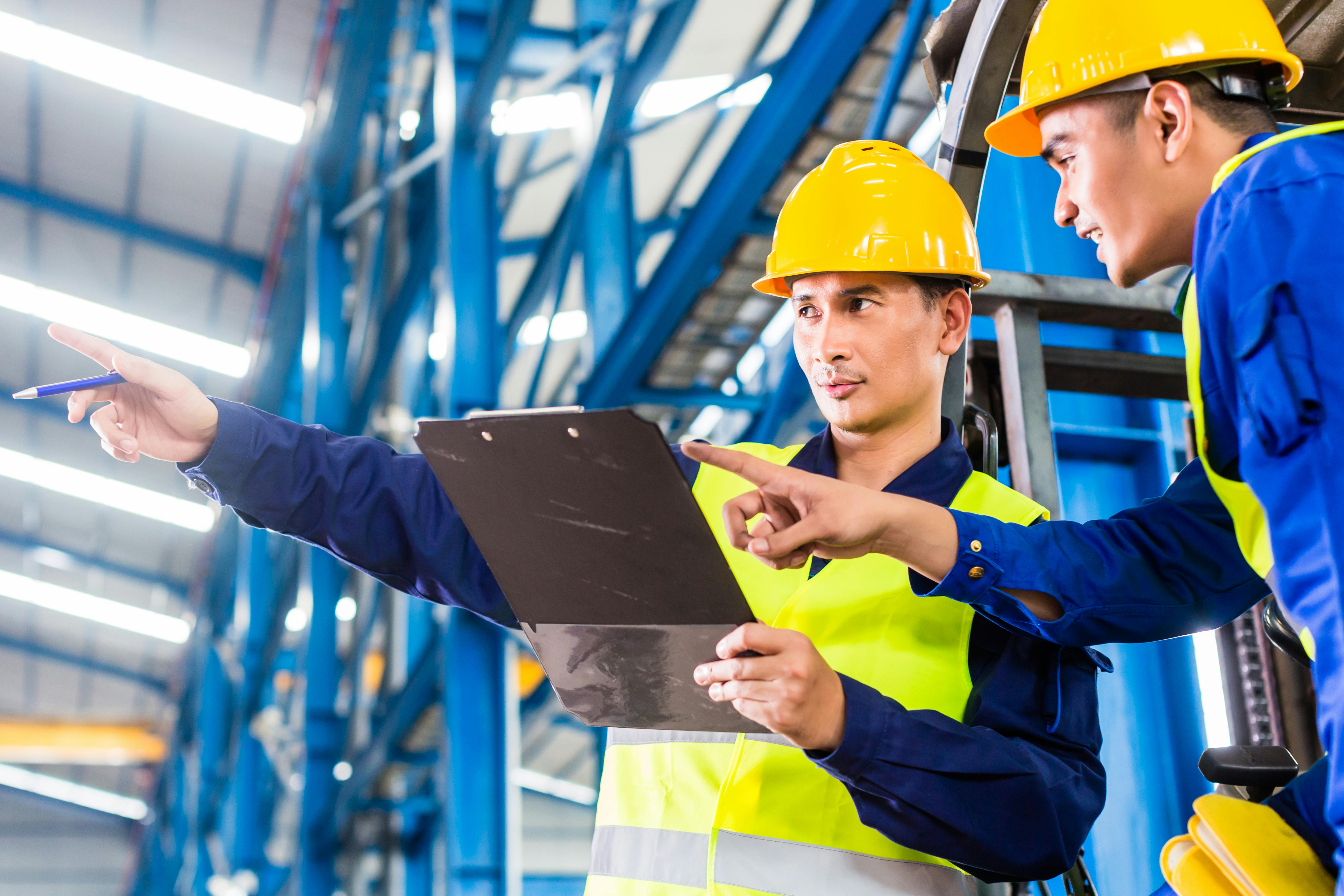Worker and forklift driver in industrial factory