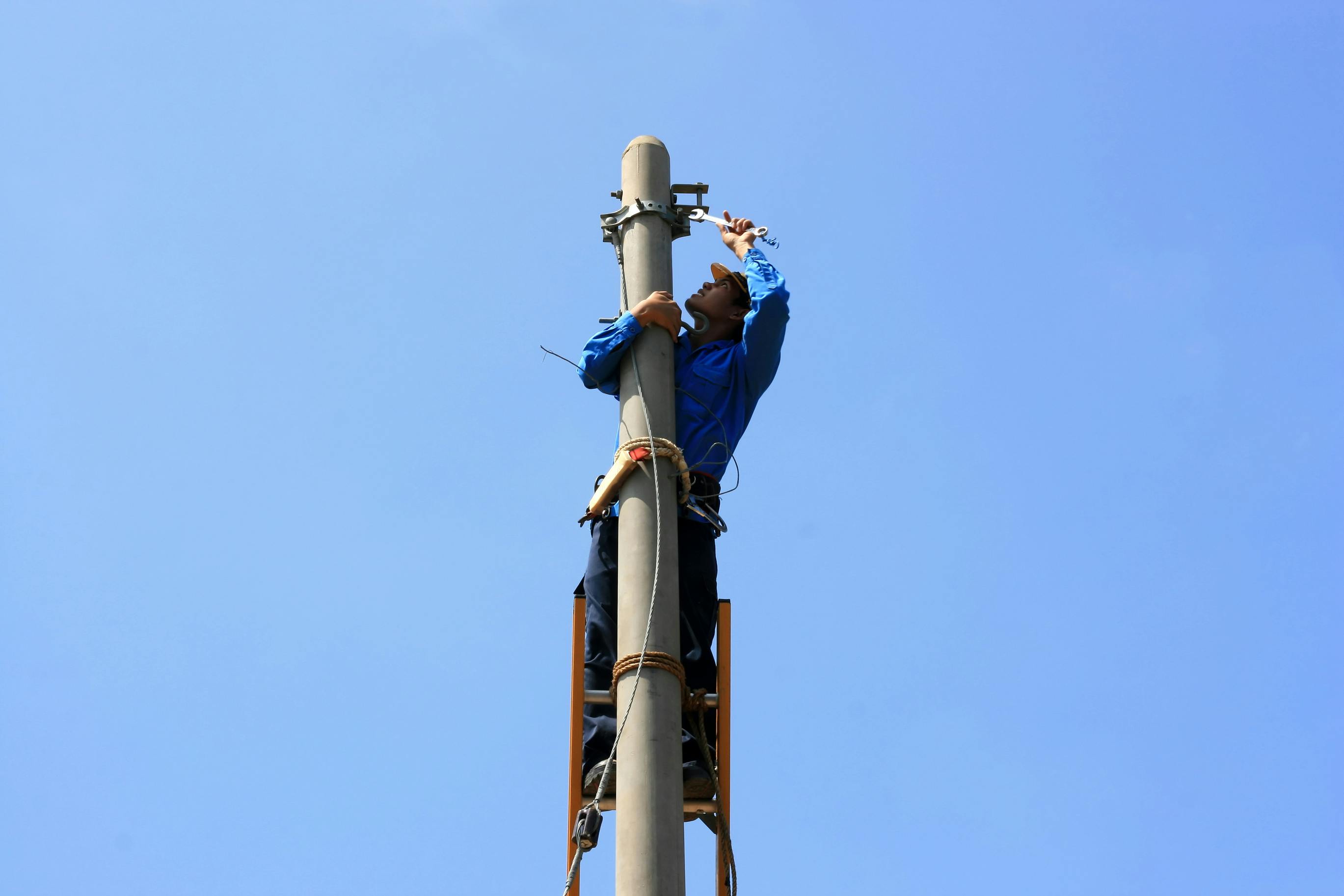 Electrician on the tower electric pole. Electrician stays on the tower electric pole and repairs a wire of the power line