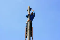 Electrician on the tower electric pole. Electrician stays on the tower electric pole and repairs a wire of the power line Electrician on the tower electric pole. Electrician stays on the tower electric pole and repairs a wire of the power line