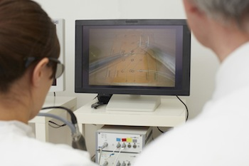 A surgeon practices sewing up a wound without a direct view. Doing so is more efficient with 3D screens.