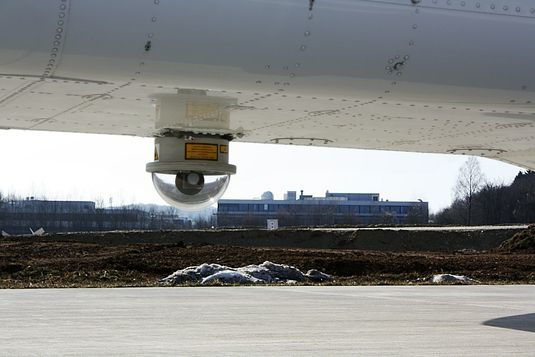The mobile telescope on the aircraft automatically tracks the position of the ground-based receiver. The incoming and outgoing light signals are directed through a tunnel in the base of the aircraft.