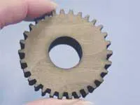 In the General Motors Futurama exhibit at the 1964/65 New York World’s Fair, a laser beam severs trees for a jungle road builder (top). Today’s CO2 lasers can cut a wooden gear from 0.5-in.-thick walnut hardwood at a speed of 85 in. per minute using power levels of 400 W (bottom). To concentrate the laser beam for cutting, a positive meniscus lens can be used to produce a 0.004-in. spot size with a 0.07-in. depth of focus. In the General Motors Futurama exhibit at the 1964/65 New York World’s Fair, a laser beam severs trees for a jungle road builder (top). Today’s CO2 lasers can cut a wooden gear from 0.5-in.-thick walnut hardwood at a speed of 85 in. per minute using power levels of 400 W (bottom). To concentrate the laser beam for cutting, a positive meniscus lens can be used to produce a 0.004-in. spot size with a 0.07-in. depth of focus.