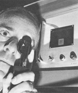 FIGURE 1. In 1965 Honeywell introduced a compact laser retina welder, which could be gripped comfortably, focused, aimed and fired with one hand by an ophthalmologist. Its portable power supply (to right of doctor) was considered compact, measuring 18 &times; 24 &times; 18 in. Myopic or hypermyopic errors could be corrected by rotating the focusing disc with the index finger. A thumb-actuated safety switch was used to fire a 500-ms burst of laser light into the patient's eye.