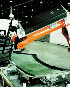 Robot-guided sealed carbon dioxide laser trims excess plastic laminate from the edges of an automobile windshield.