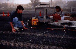 FIGURE 1. Virginia Tech students Dave Forbis and Cindi Grinder install extrinsic Fabry-Perot interferometric fiberoptic sensors in testbed on Virginia Tech campus. The sensors were later covered with asphalt.