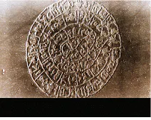 FIGURE 6. UV-emitting lasers have been used to etch microstructures pixel by pixel directly onto photoresists. This micrograph shows the Disk of Festos etched onto photoresist. The image is 200 × 200 pixels wide, with a pixel size of 3 µm. The total size is 0.6 mm—300 times smaller than the original—making this the smallest copy of the Disk of Festos ever made. The same technology—pixelated patterning by controlled microetching—is used to make microlens arrays. Festos was an ancient city in Crete, Greece. The disk dates from 1600 B.C. and is covered with hieroglyphics stamped into wet clay with a metal stamp—a very ancient precursor of printing. FIGURE 6. UV-emitting lasers have been used to etch microstructures pixel by pixel directly onto photoresists. This micrograph shows the Disk of Festos etched onto photoresist. The image is 200 × 200 pixels wide, with a pixel size of 3 µm. The total size is 0.6 mm—300 times smaller than the original—making this the smallest copy of the Disk of Festos ever made. The same technology—pixelated patterning by controlled microetching—is used to make microlens arrays. Festos was an ancient city in Crete, Greece. The disk dates from 1600 B.C. and is covered with hieroglyphics stamped into wet clay with a metal stamp—a very ancient precursor of printing.