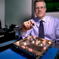 An integrated photonic circuit with a size similar to the chip held by NASA researcher Mike Krainak will replace the fiber-optic receiver in the lower portion of the photo. The new modem will be tested on the International Space Station. An integrated photonic circuit with a size similar to the chip held by NASA researcher Mike Krainak will replace the fiber-optic receiver in the lower portion of the photo. The new modem will be tested on the International Space Station.