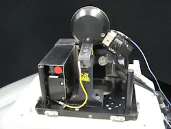 A miniature MRF polishing head with an improved fluid-delivery system is small enough to fit on an end table. The polishing wheel is at the top; the ribbon of MR fluid is held on the wheel’s rim. A miniature MRF polishing head with an improved fluid-delivery system is small enough to fit on an end table. The polishing wheel is at the top; the ribbon of MR fluid is held on the wheel’s rim.