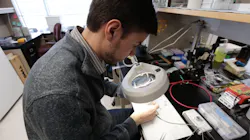 Baris Ozbay examines the tiny laser-scanning microscope. Baris Ozbay examines the tiny laser-scanning microscope.