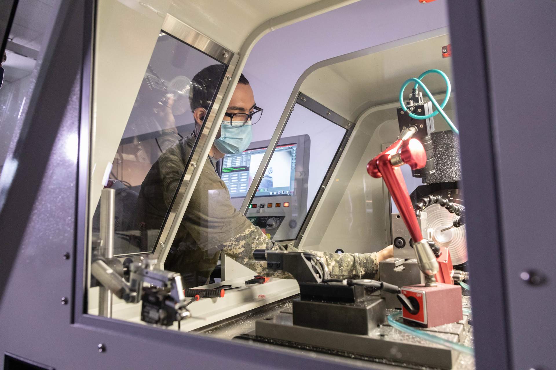 A student in the Optical Systems Technology program at Monroe Community College learns to operate the Moore Nanotechnology Systems 250 UPL diamond-turning machine.