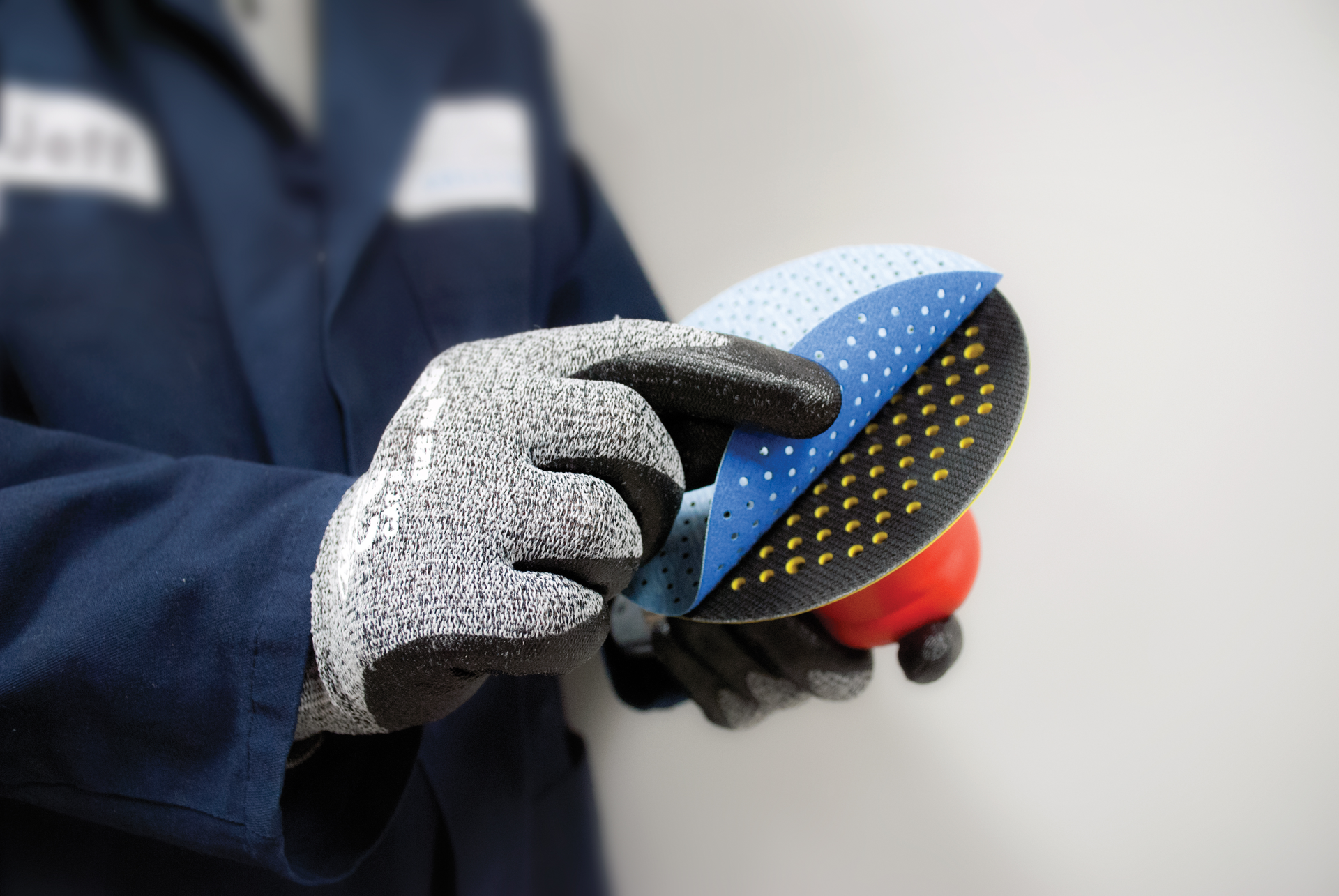 FIGURE 1. A laser-cut, multi-hole abrasive disc is attached to a backup pad for use on a dual-action pneumatic sander.