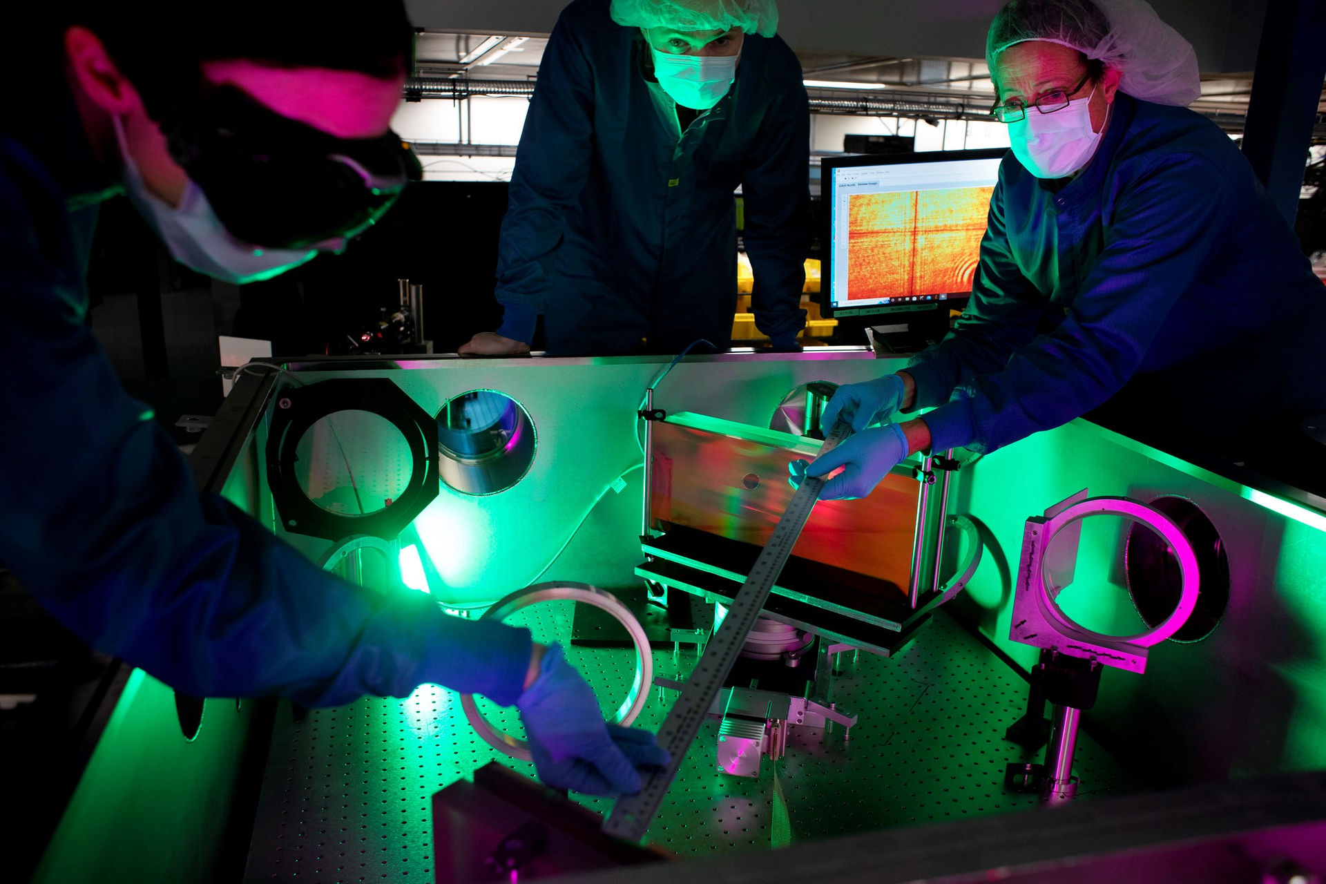 (L-R) Laser engineer Lauren Weinberg, research scientist John Nees, and research engineer Galina Kalinchenko pose for photos while working on the ZEUS laser at the NSF ZEUS laser facility in a Michigan Engineering lab.