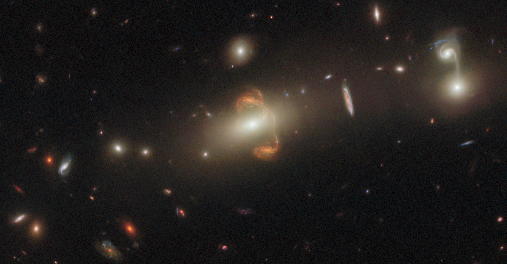 A gravitationally lensed galaxy, captured by the Hubble Space Telescope. A mirror image of the galaxy is at the center.