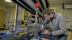 Jonathan Kwolek places a light-delivery system carefully around a custom vacuum chamber to align the optics within the custom light-delivery system to optimize the atomic beam in the NRL Atom Interferometry Lab. Jonathan Kwolek places a light-delivery system carefully around a custom vacuum chamber to align the optics within the custom light-delivery system to optimize the atomic beam in the NRL Atom Interferometry Lab.