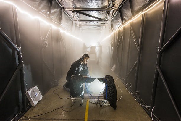 Image: Sandia National Laboratories developed a fog chamber to test optics, like security camera sensors, in a controlled environment. Sandia chemical engineer Andres Sanchez checks an instrument that measures the particle size and concentration of the fog in the chamber&rsquo;s atmosphere.