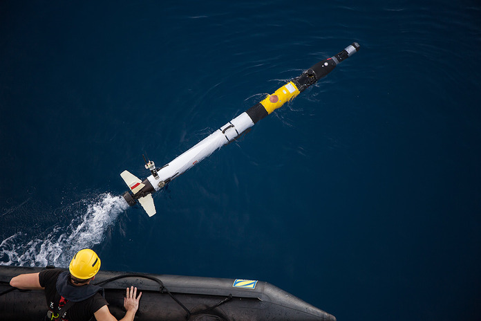 A team member launches an Iver autonomous underwater vehicle AUV On the rear is the transceiver fins and thruster