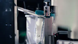 A test tube is positioned for having its cap removed. Several COVID-19 test swaps are in the tube, part of pool-processing approach. A test tube is positioned for having its cap removed. Several COVID-19 test swaps are in the tube, part of pool-processing approach.